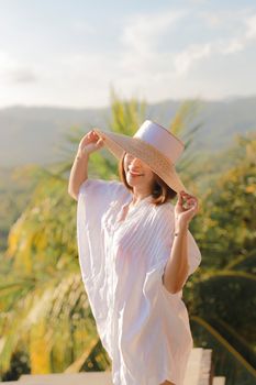 Bright sunny day in Bali featuring a smiling woman in a sun hat enjoying the outdoors.