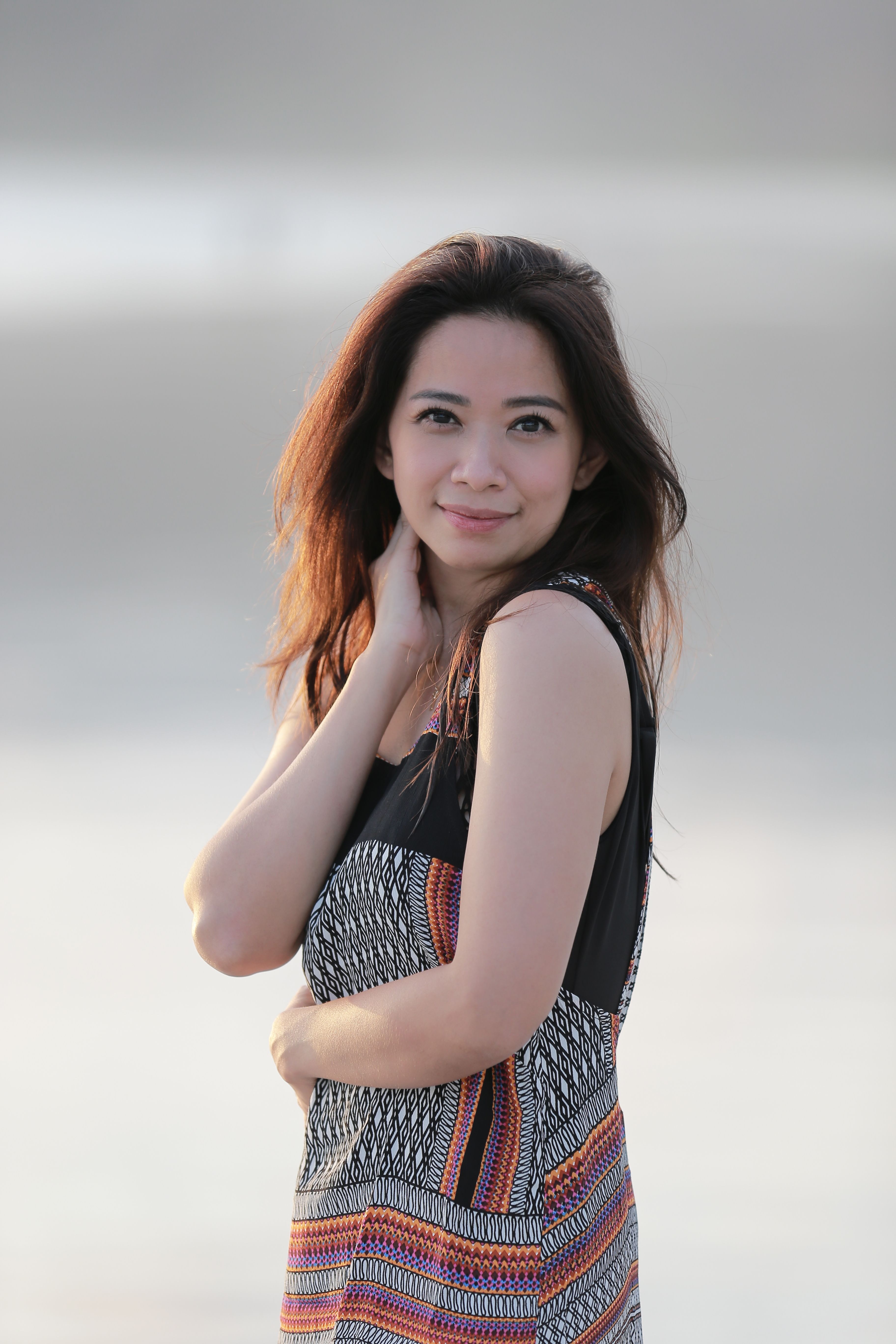A woman enjoys a peaceful moment on a Bali beach, embracing the natural beauty during a sunset.