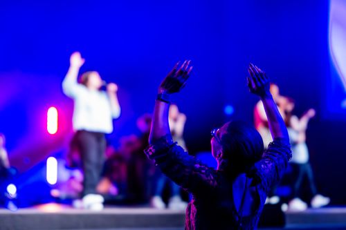 Free A lively concert scene with an engaged audience member raising hands, set against vivid blue lighting. Stock Photo