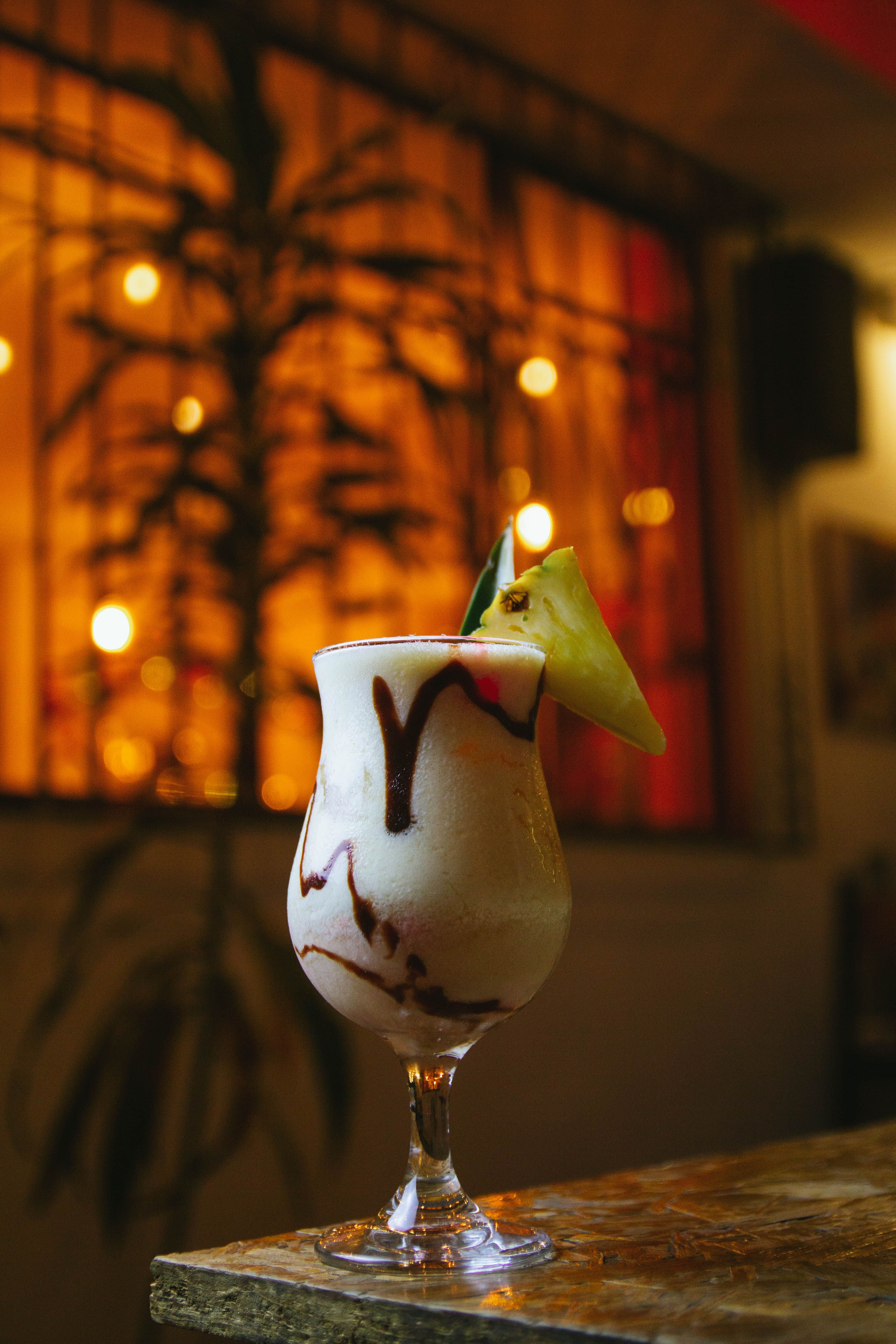 A tall glass of orange-red Bahama Mama cocktail layered with grenadine at the bottom, garnished with a pineapple wedge and maraschino cherry on a bamboo skewer.