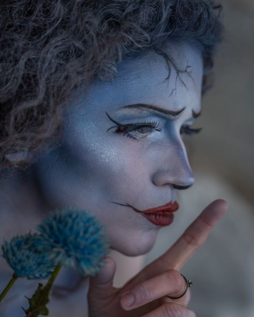 Free Close-up portrait of a woman with eerie Halloween makeup, holding a blue thistle flower in Stockholm. Stock Photo