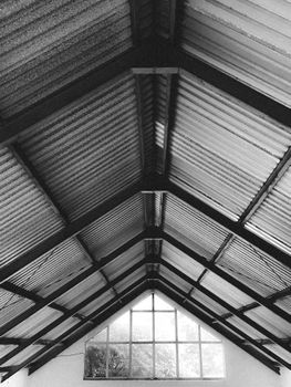 Artistic black and white view of a symmetrical attic roof with windows.