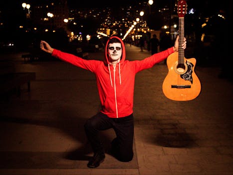 A performer in makeup holding a guitar at night; festive and lively atmosphere.