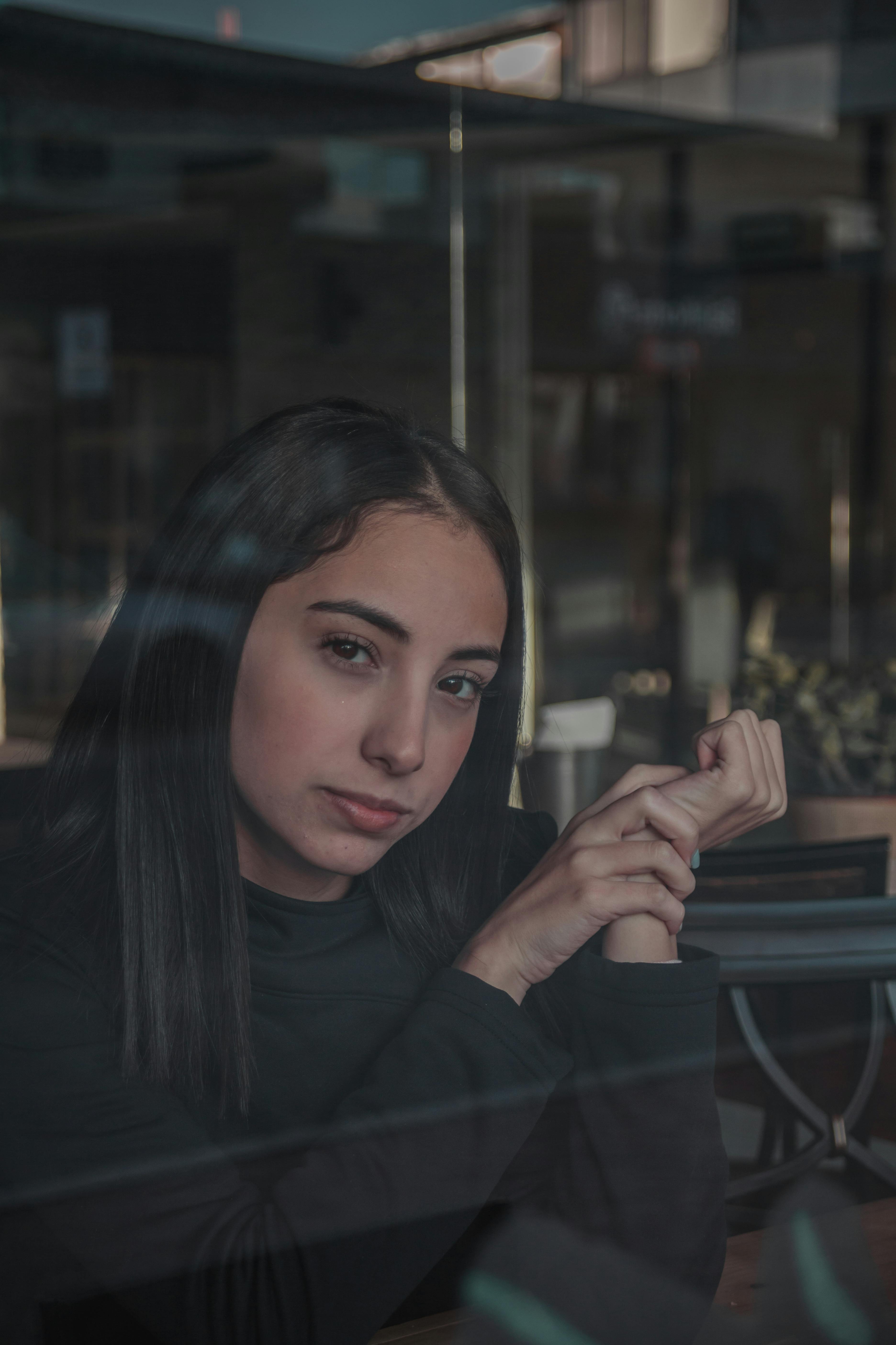 在墨西哥恩塞纳达，透过反光窗拍摄的一名女子喜怒无常的室内肖像