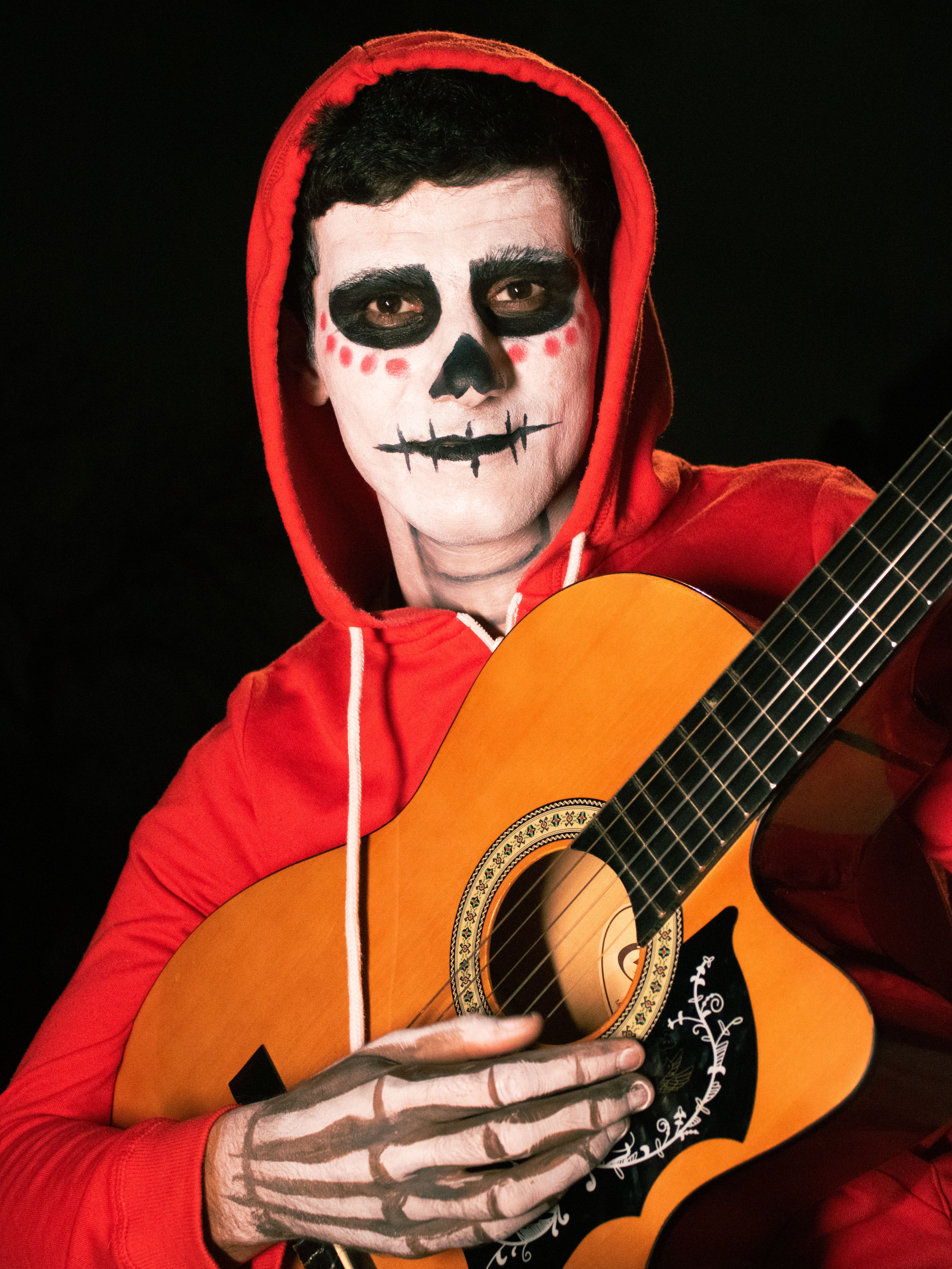 Man in skeleton makeup playing guitar, celebrating Day of the Dead.