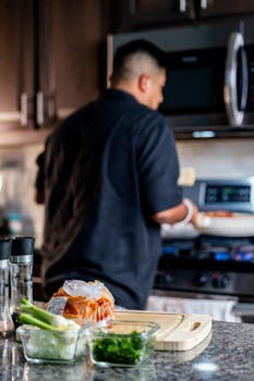 A person cooking in a modern kitchen with fresh ingredients on the countertop.