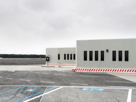 Minimalistic airport building adjacent to an open tarmac with overcast sky.