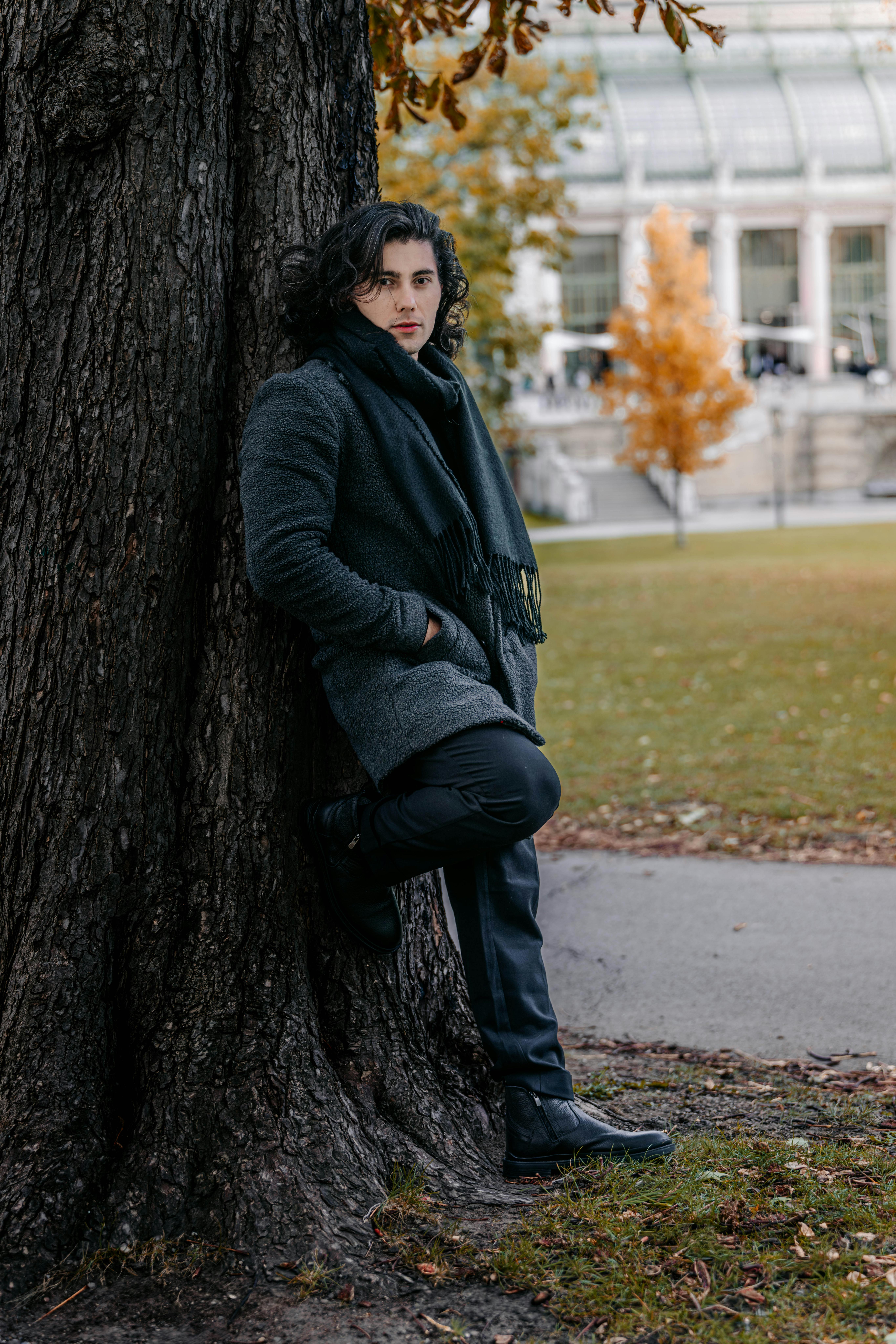 bezplatná Elegantní muž v podzimní módě opírající se o strom ve vídeňském parku Základová fotografie