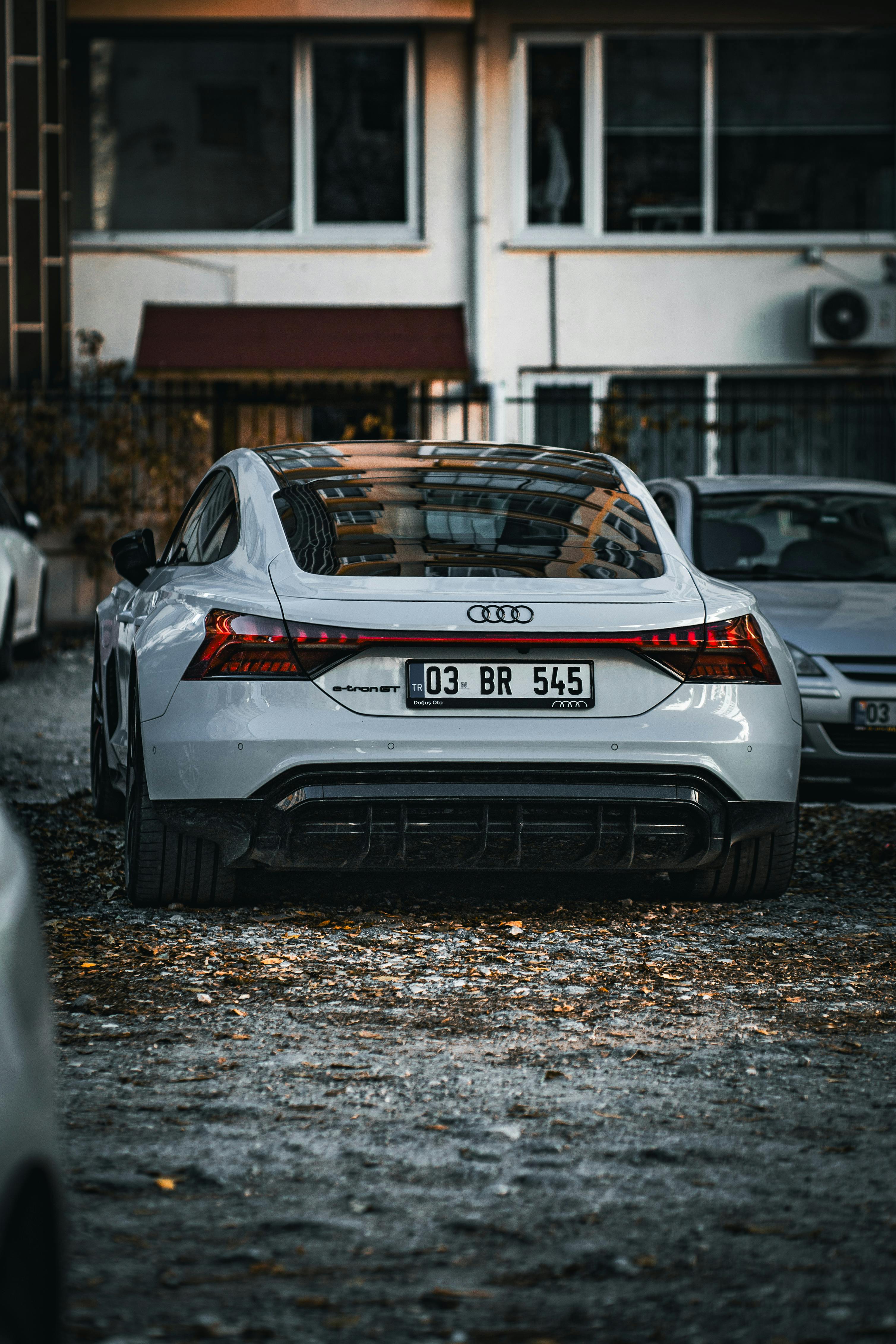 Free A modern Audi parked on a gravel driveway outside a building, showcasing rear design and urban setting. Stock Photo