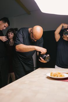Group of photographers in a studio capturing a plate of food, highlighting culinary art.