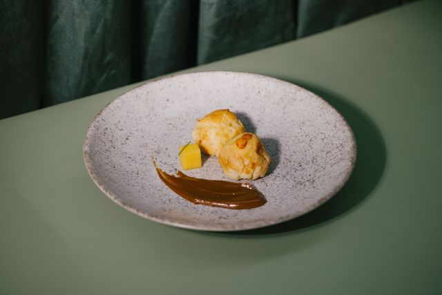 A modern presentation of Brazilian dessert with chocolate sauce and mango on a stylish plate.