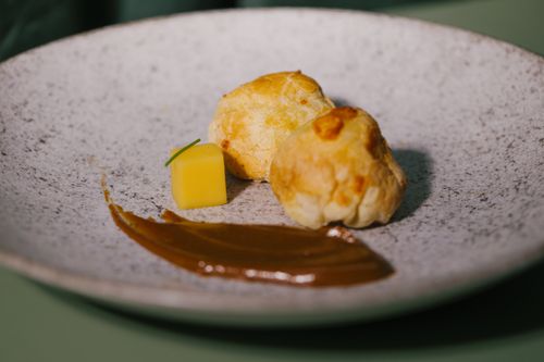 Free A sophisticated presentation of Brazilian pastry with sauce on a textured grey plate. Stock Photo