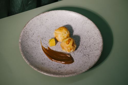 Free Elegant Brazilian dessert featuring golden puffs and caramel on a speckled plate. Stock Photo