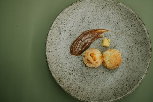 Photo by Emanuel Pedro Elegantly plated gourmet pastry with sauce on a rustic stone-like plate, perfect for culinary presentations.