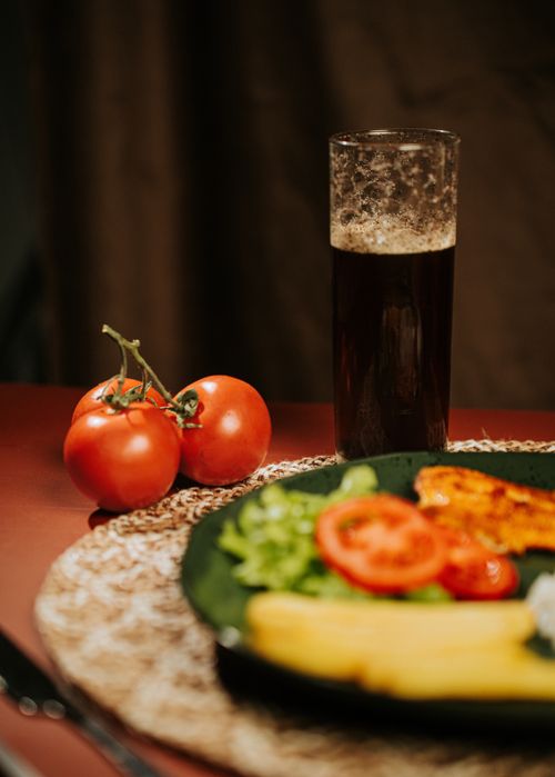 Free A healthy meal with vegetables, fish, and a glass of dark beer on a wooden table. Stock Photo