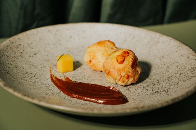 Elegant presentation of gougères with sauce on a speckled plate, highlighting gourmet cuisine.