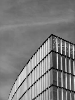 Black and white photo of a modern glass building with a cloudy sky in Santiago, Chile.