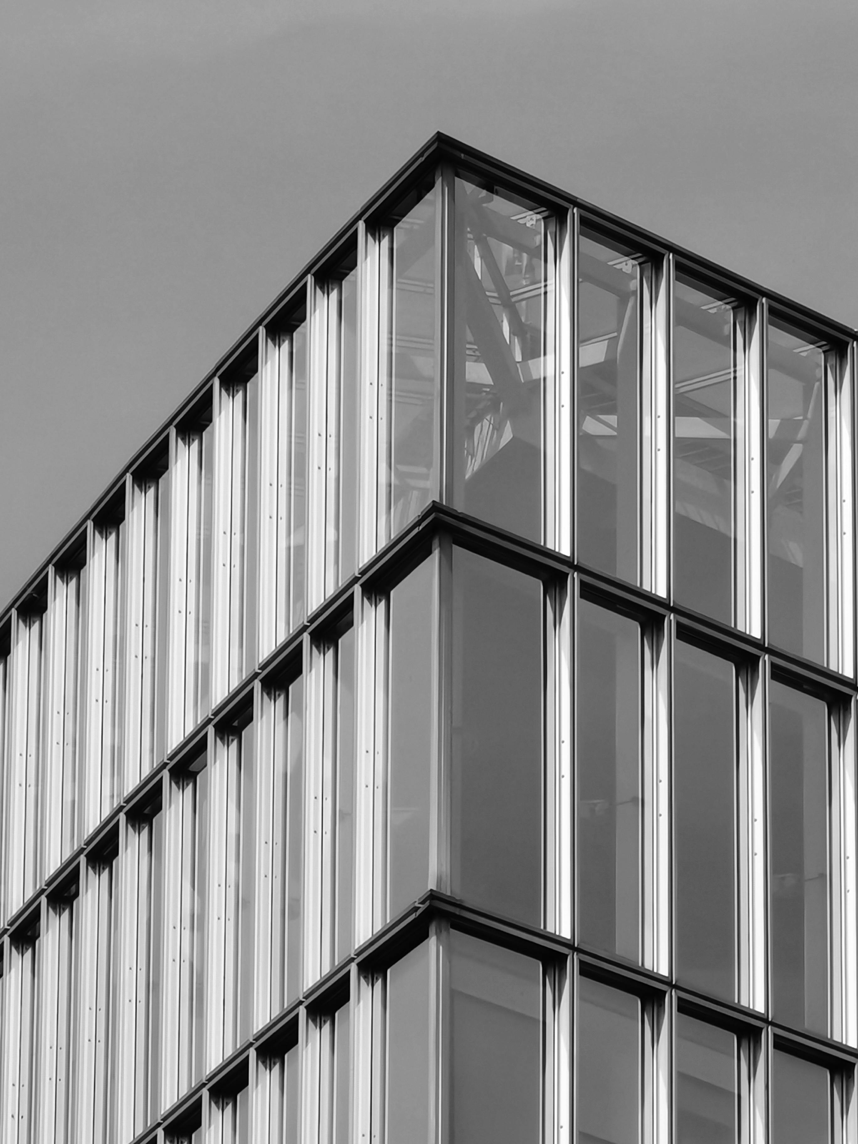 grátis Elegante fotografia em preto e branco da fachada de um edifício moderno de vidro com padrões geométricos. Foto profissional