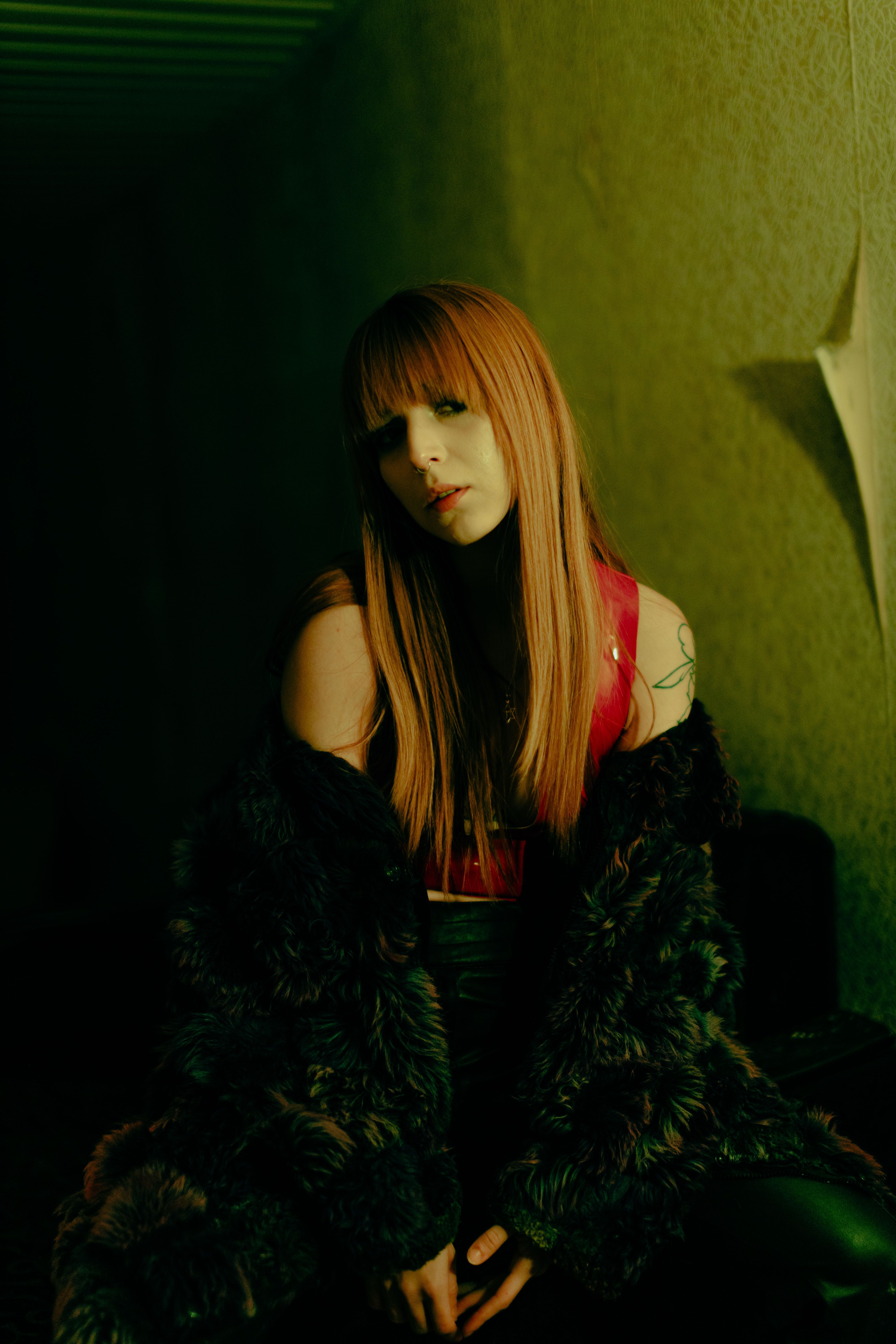 Moody portrait of a woman with red hair in fur coat, dim lighting.