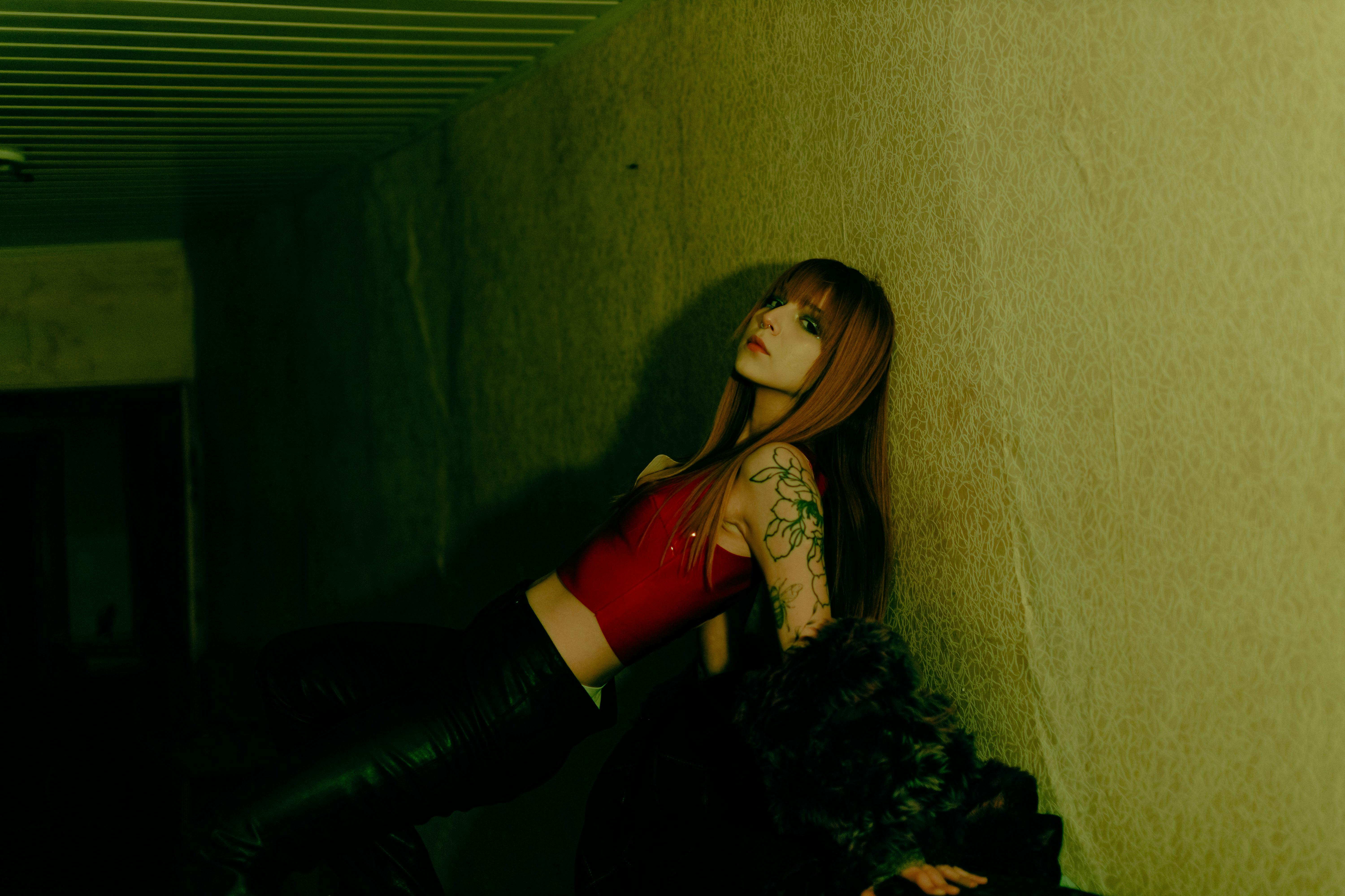 Bezpłatne Stylowa kobieta z tatuażami pozuje w nastrojowym wnętrzu. Zdjęcie z galerii