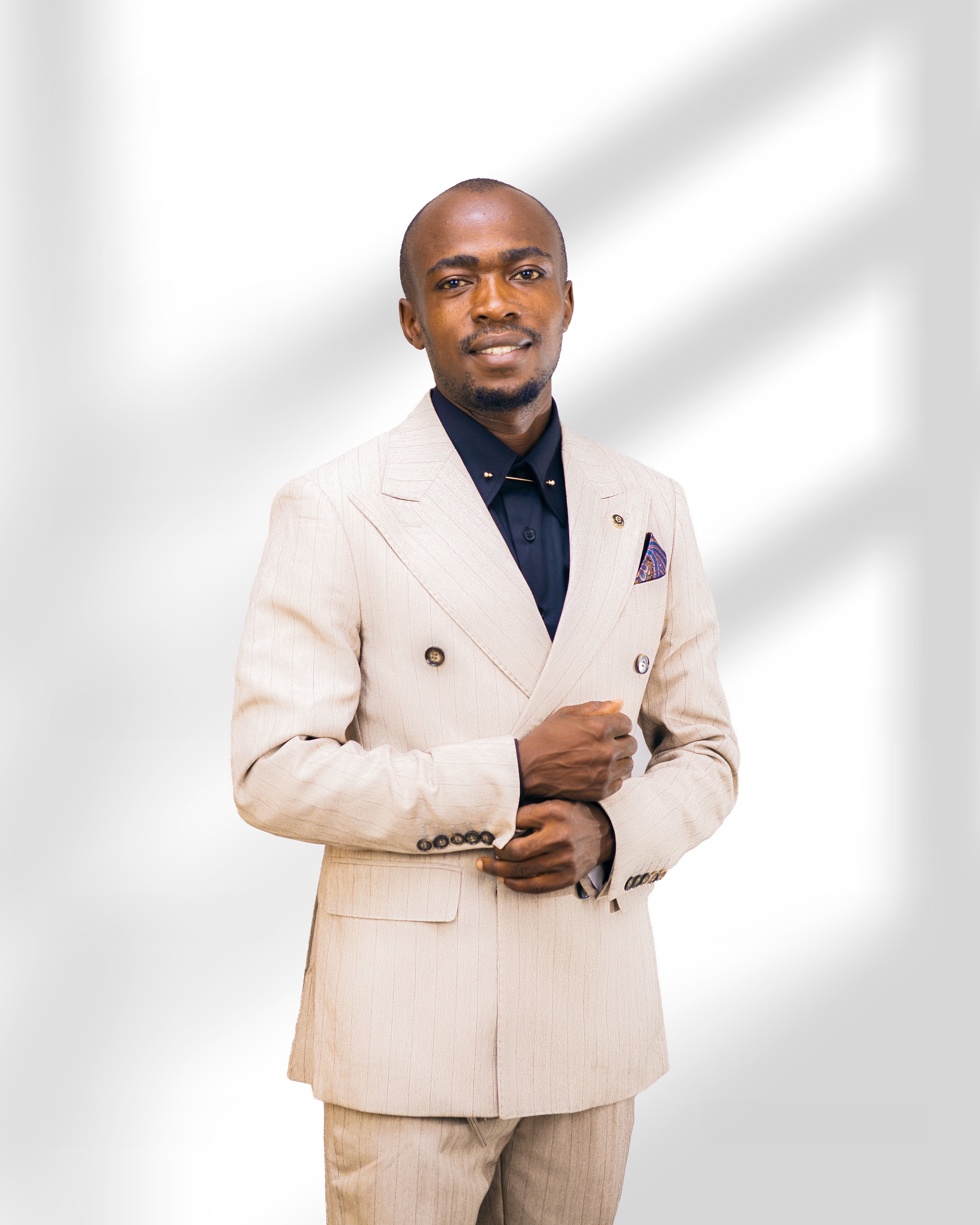 Confident man in beige suit posing against a bright background.