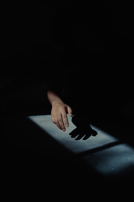 Silhouette of a hand in dramatic low-light casting a shadow. High contrast effect.