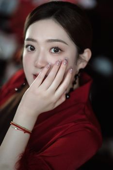 Portrait of an elegant woman in a vibrant red outfit showcasing stylish nail art.