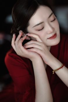 Elegant woman in a red dress, eyes closed, showing tranquility and style.