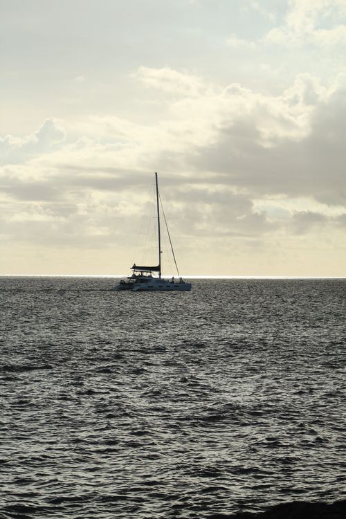 Free A tranquil sailboat on the ocean during a peaceful sunset with cloudy sky. Stock Photo