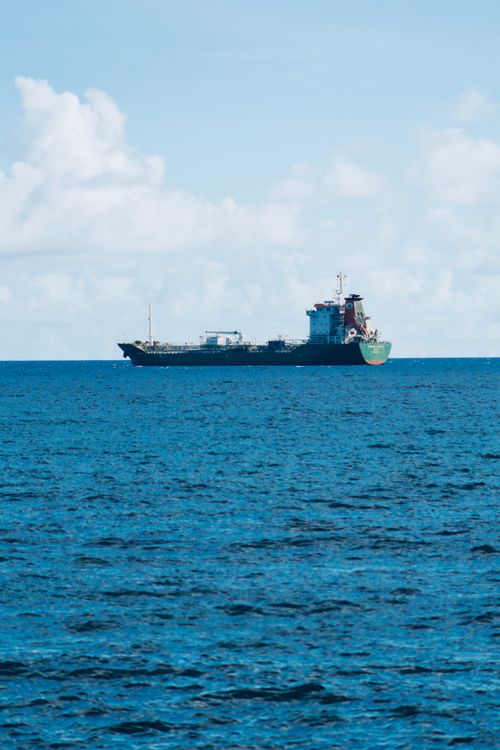Free A cargo ship sails through the blue ocean under a clear sky, epitomizing maritime trade. Stock Photo