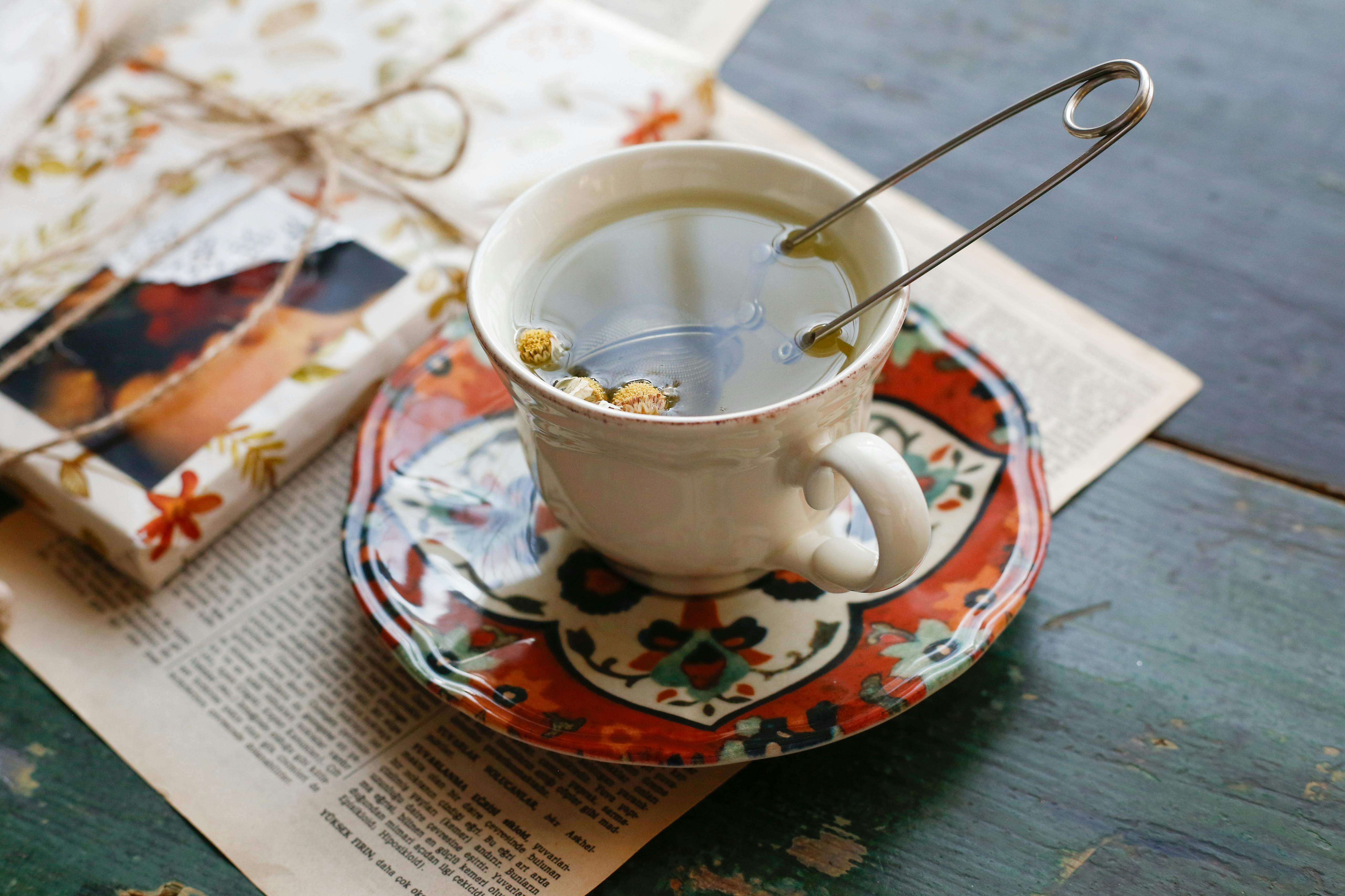 Delicate tea setup featuring chamomile tea in a floral cup, with a rustic vibe on an aged table.