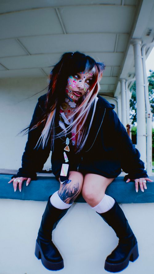 Free Portrait of a woman with tattoos, colorful makeup, and edgy fashion outdoors. Stock Photo
