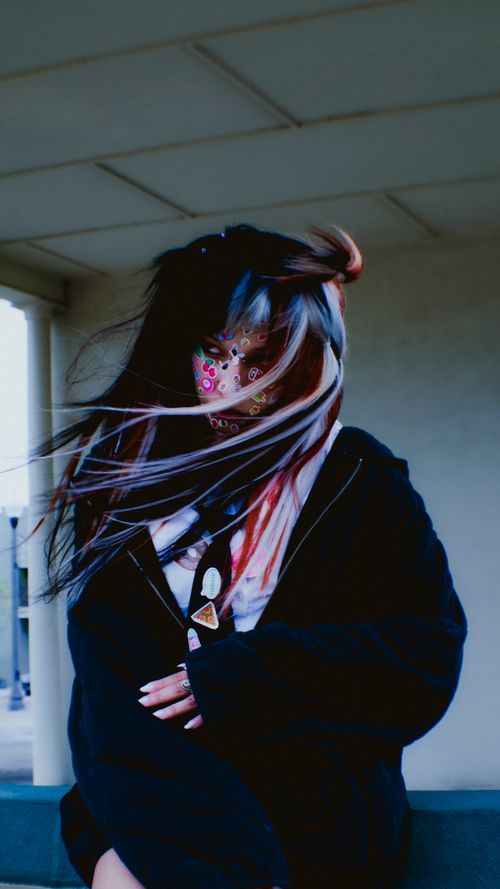 Free A person with a decorative face mask stands in a windy exterior setting, lending an air of mystery. Stock Photo