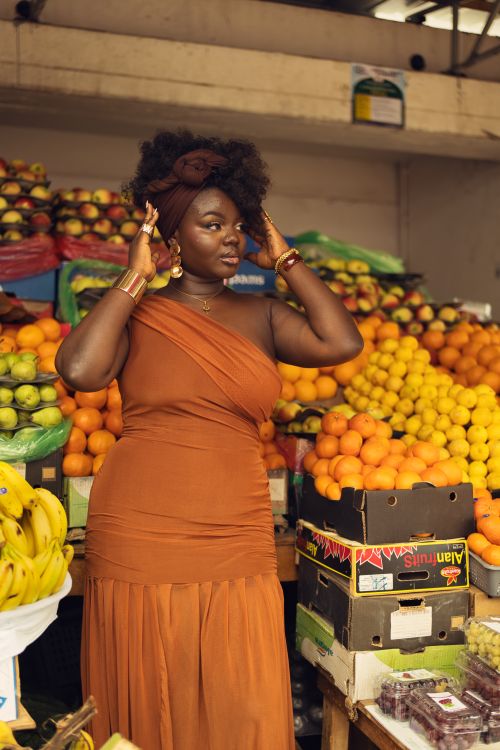 Free Woman posing amidst vibrant fruits in a bustling African market. Stock Photo