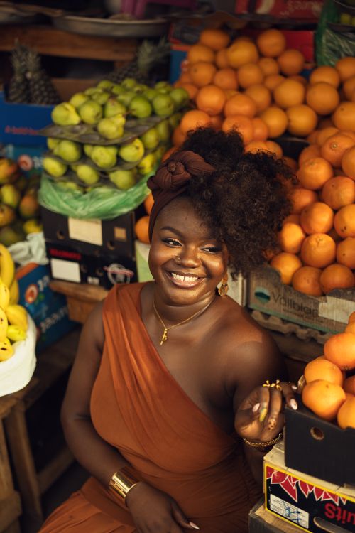 Free Joyful woman in a colorful fruit market. Vibrant citrus and tropical fruits create a warm atmosphere. Stock Photo