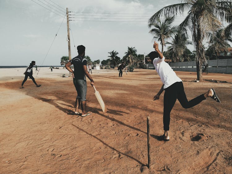 Men Playing Cricket At Beach