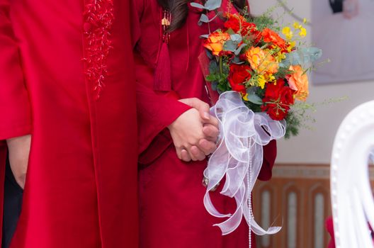 A couple in vibrant red clothing holding hands with a colorful flower bouquet. Perfect for wedding themes.