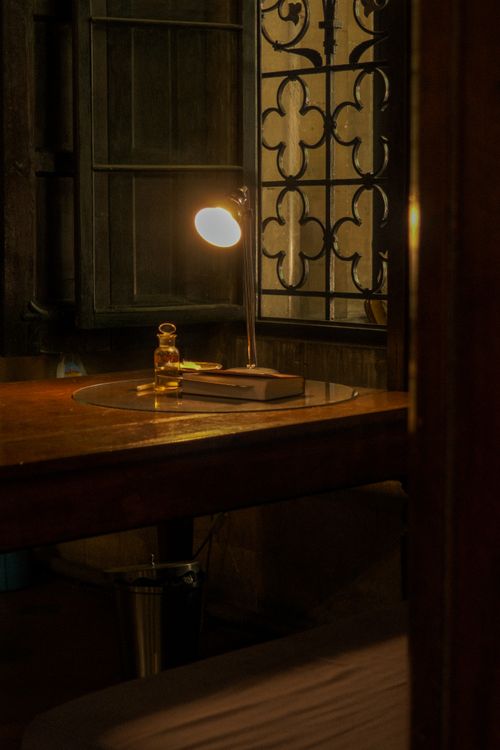 Free A dimly lit vintage desk with a lamp and elegant decor creates a warm ambiance. Stock Photo