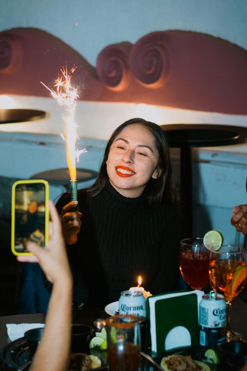 Free Woman happily celebrating birthday with sparkler at a party. Stock Photo