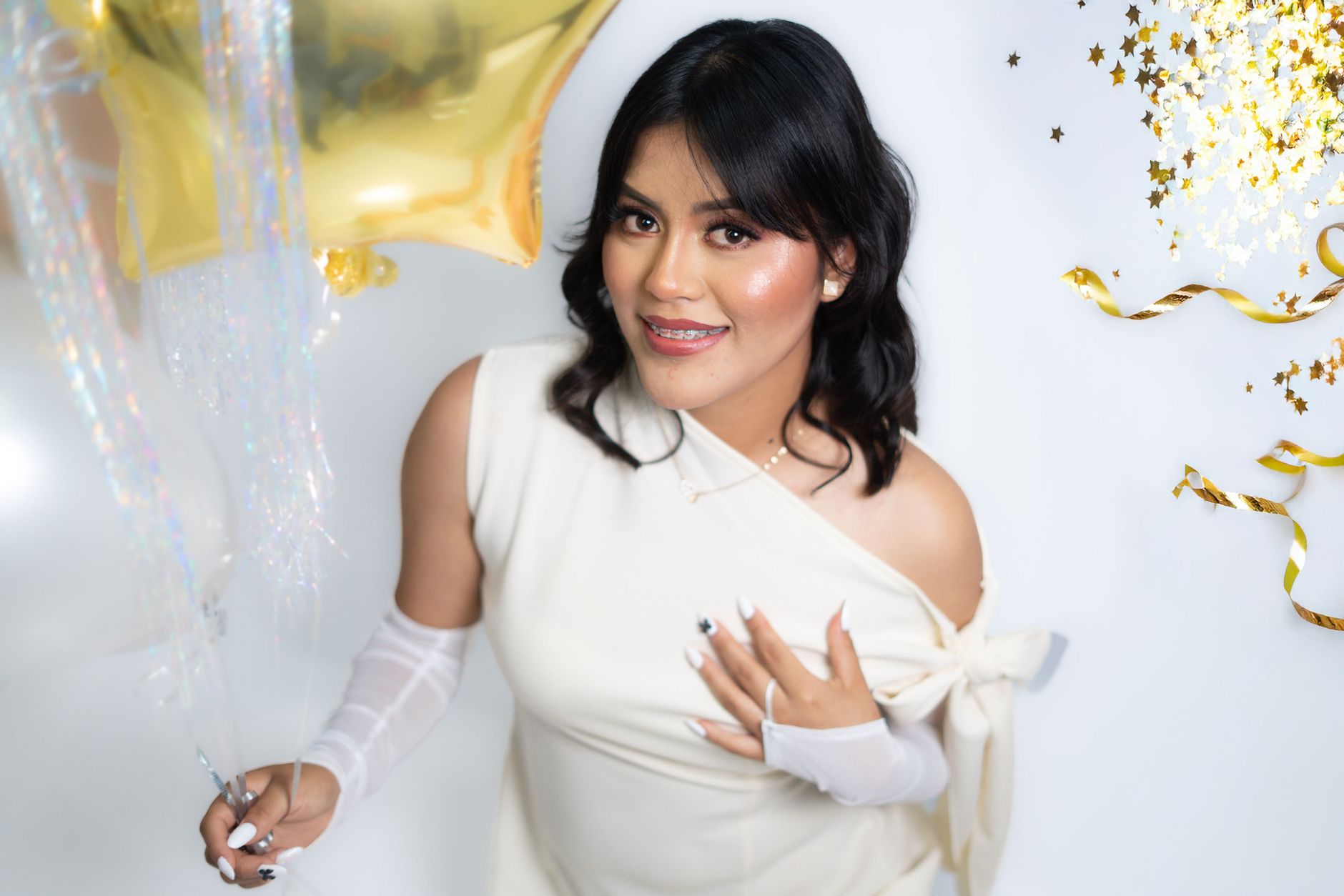 Stylish woman in elegant attire with balloons and festive decorations.