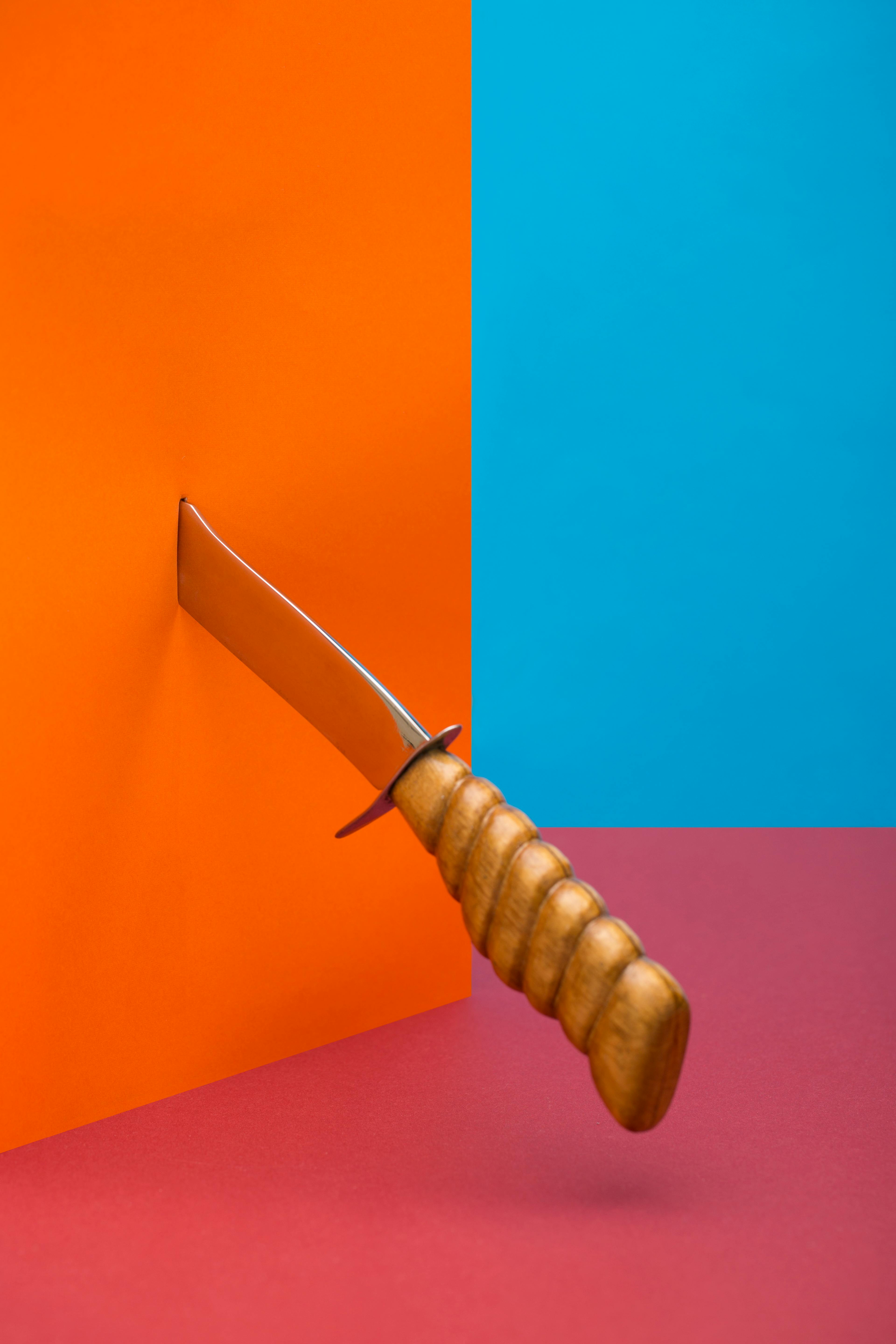 De franc Imatge artística d'un ganivet que perfora un fons taronja i blau vibrant. Foto d'estoc