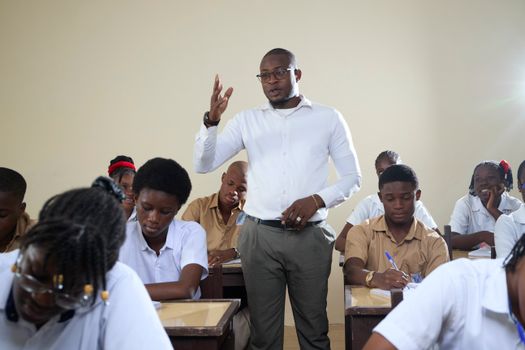 Teacher interacting with high school students in a classroom setting.