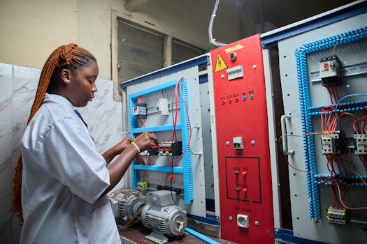 Photo by mickael ange konan Young female technician repairing electrical control panel in industrial setting.