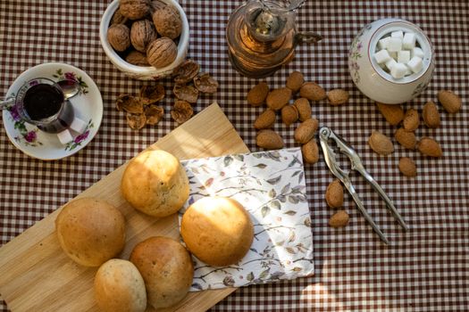 Rustic breakfast setup featuring freshly baked bread, nuts, and tea on a checkered tablecloth, creating a cozy ambiance.