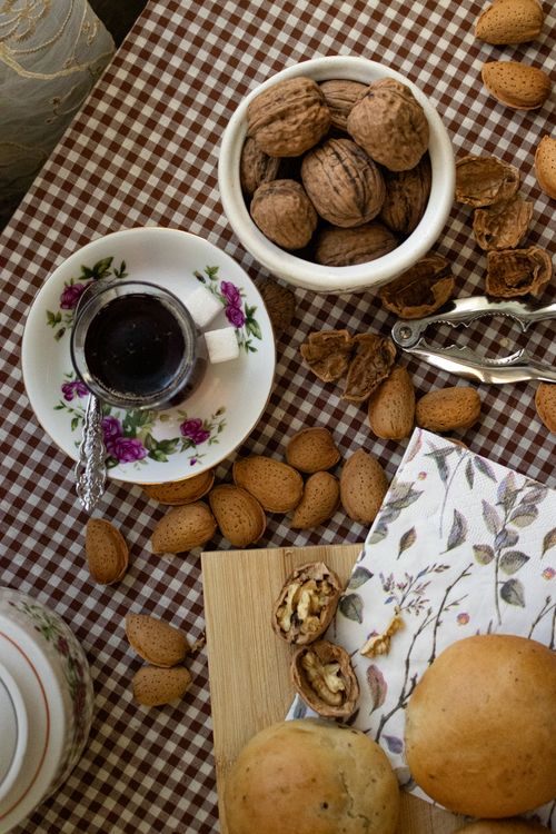 Free A cozy setup of a rustic breakfast featuring tea, walnuts, and almonds on a checkered tablecloth. Stock Photo