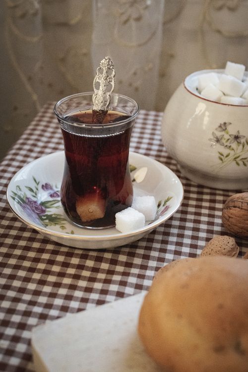 Free A warm, inviting scene of traditional tea served with sugar cubes and walnuts on a checkered tablecloth. Stock Photo