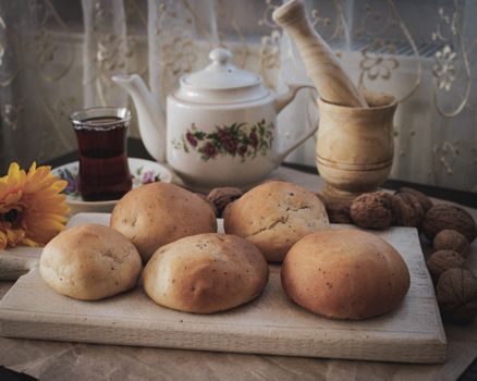 A warm and inviting scene featuring fresh buns, tea, and walnuts, perfect for a cozy morning.
