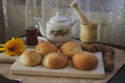 A cozy setup featuring fresh baked rolls, a floral teapot, and tea, perfect for an afternoon tea break.