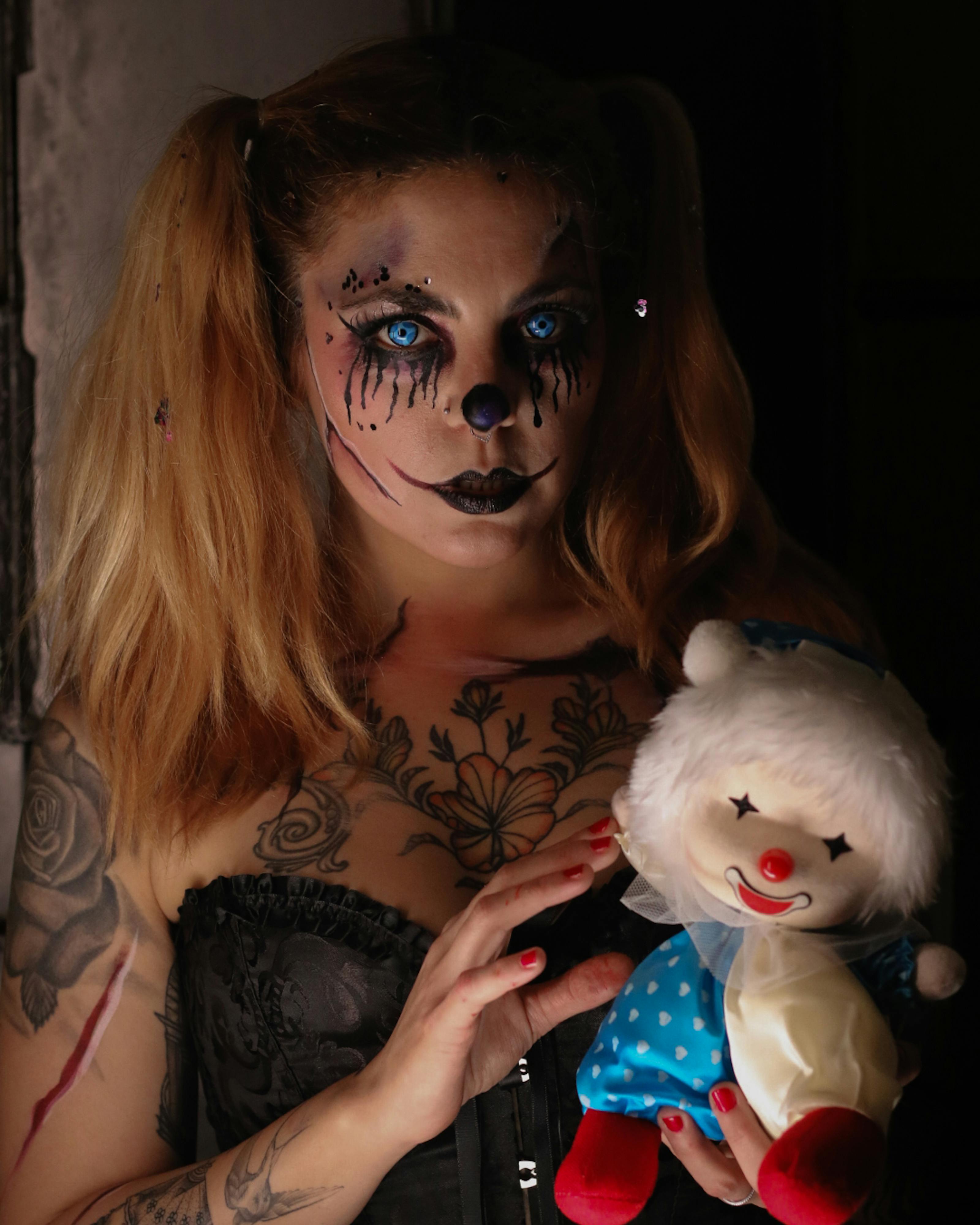 Ücretsiz Oyuncak palyaço bebeği tutan palyaço makyajlı kadın, ürkütücü temalar için mükemmel. Stok Fotoğraflar