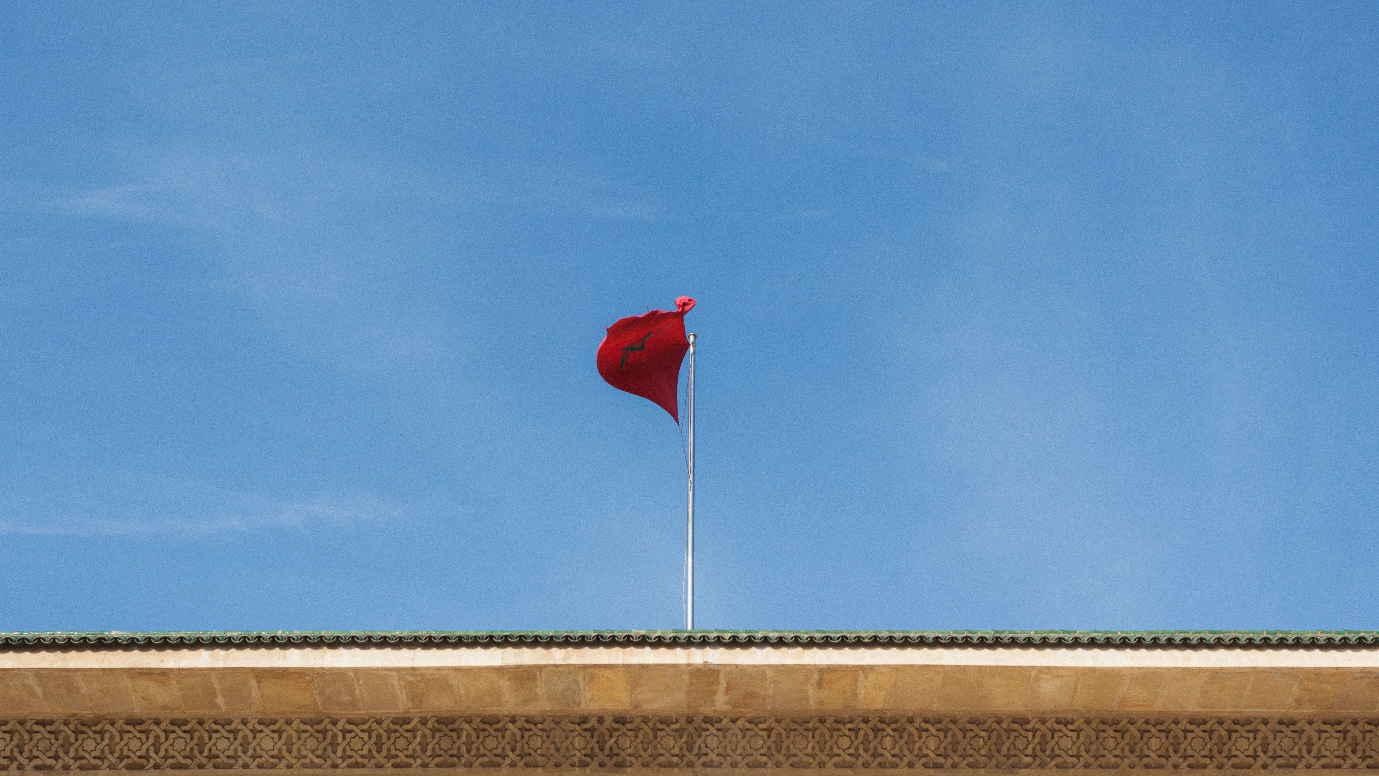 Moroccan supporters waving red flags outside a crowded stadium before a World Cup knockout fixture